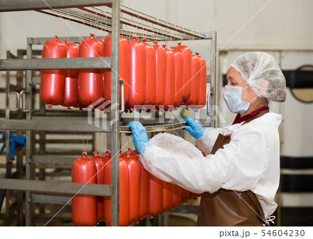 Female carrying sausages on racks Female carrying sausages on racks 54604230