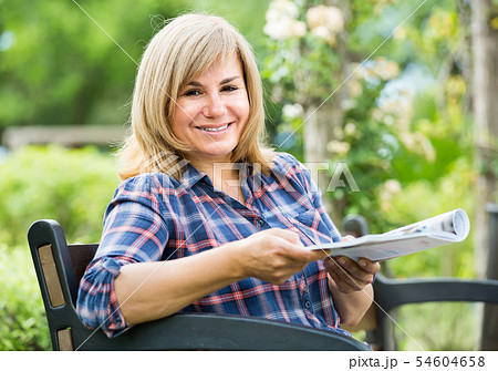 mature woman with magazine in garden . mature woman with magazine in garden . 54604658