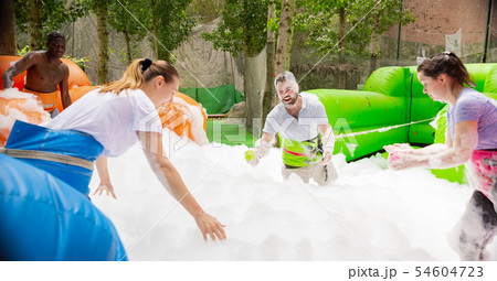 Game of funny friends in soap suds on an inflatable trampoline Game of funny friends in soap suds on an inflatable trampoline 54604723