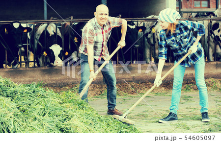 Farm employees with pitchforks near barn Farm employees with pitchforks near barn 54605097