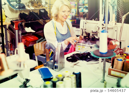 middle-aged woman tailor using sewing machine 54605437