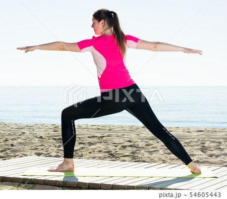 Woman training yoga poses on beach Woman training yoga poses on beach 54605443