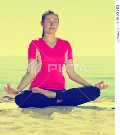 Woman exercising yoga poses on beach Woman exercising yoga poses on beach 54605588