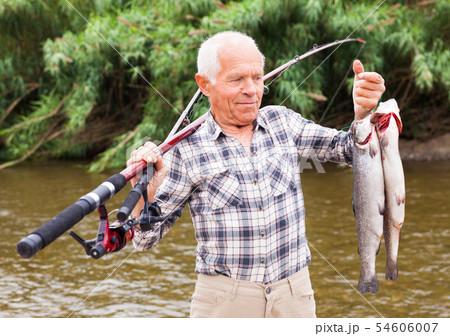 Mature fisherman examining catch Mature fisherman examining catch 54606007