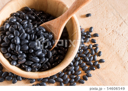Raw black beans in wooden bowl and spoon on table. Raw black beans in wooden bowl and spoon on table. 54606549