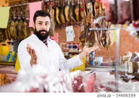 Man shop assistant showing meat in shop Man shop assistant showing meat in shop 54606599