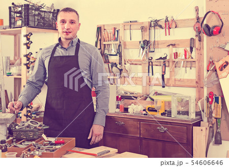 Portrait of young handsome carpenter in uniform in workshop. Portrait of young handsome carpenter in uniform in workshop. 54606646