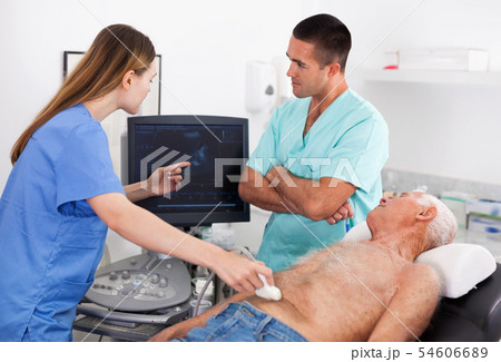 Two confident sonographers working together examining patient with modern ultrasound machine 54606689