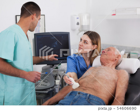 Woman and man doctors examines a senior man at abdomen Woman and man doctors examines a senior man at abdomen 54606690