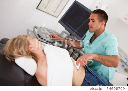 Man doctor examines a mature woman at abdomen with ultrasound Man doctor examines a mature woman at abdomen with ultrasound 54606709