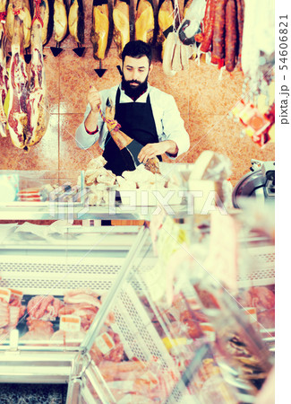 Male shop assistant demonstrating jamon Male shop assistant demonstrating jamon 54606821