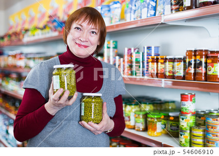 woman choosing canned jar of green peas woman choosing canned jar of green peas 54606910