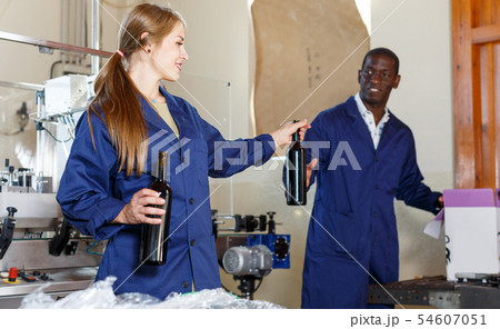 Woman and man packing bottles with new wine in box at winery Woman and man packing bottles with new wine in box at winery 54607051