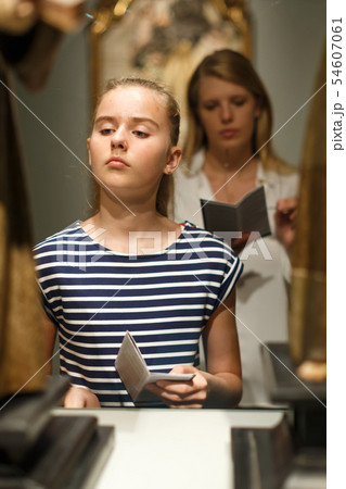 Girl looking at art objects in museum and using guidebook 54607061