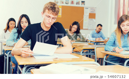 Schoolboy is learning and answering the question on paper 54607132