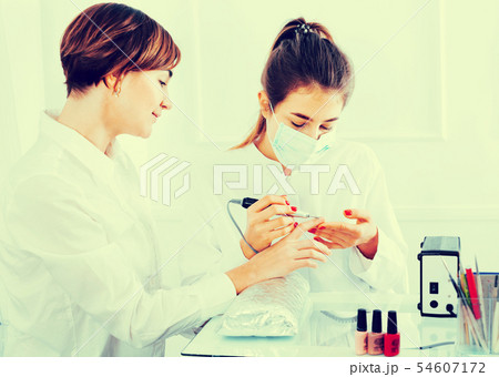 Female client doing nails in shellac technique Female client doing nails in shellac technique 54607172