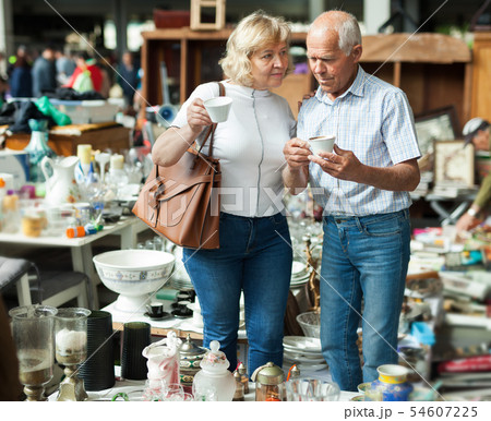 Mature family couple choosing vintage dishes on street market Mature family couple choosing vintage dishes on street market 54607225