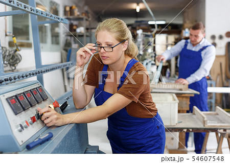 Female glazier working on glass bevelling machine 54607548