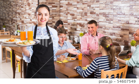 Girl is ready to serve salad and juice to young visitors Girl is ready to serve salad and juice to young visitors 54607549