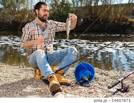 Adult male fisherman holding fish in his hands Adult male fisherman holding fish in his hands 54607873