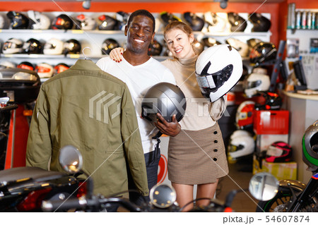 Smiling female and male customers satisfied with purchases in motorcycle shop Smiling female and male customers satisfied with purchases in motorcycle shop 54607874