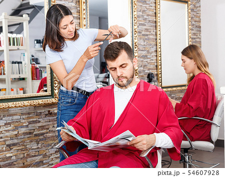 Cheerful woman professional hairdresser cut male's hair in hairdressing salon 54607928