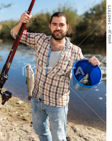 Happy fisherman with caught fish on a hook and a fishing rod in his hands Happy fisherman with caught fish on a hook and a fishing rod in his hands 54607975