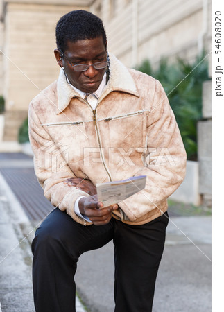 Man in overcoat reading guidebook 54608020