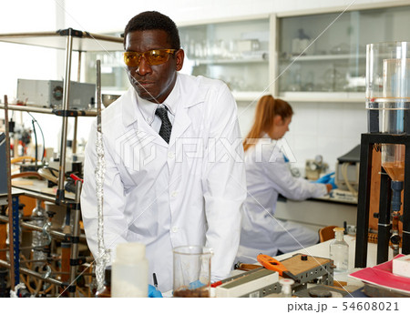 Man lab technician in glasses performing experiments and writing results Man lab technician in glasses performing experiments and writing results 54608021