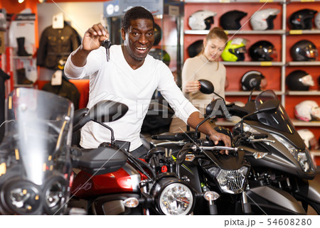 Smiling Afro American man posing near motorcycle Smiling Afro American man posing near motorcycle 54608280
