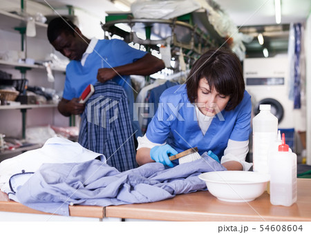 Woman dry cleaning clothes in laundry Woman dry cleaning clothes in laundry 54608604
