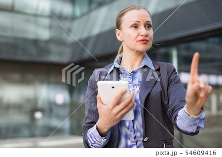 Female with digital tablet looking on finger in the city Female with digital tablet looking on finger in the city 54609416