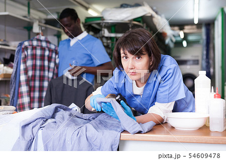 Woman dry cleaning clothes in laundry 54609478