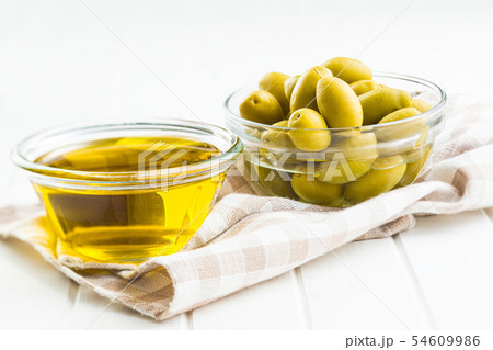 Green olives and olive oil in glass bowl. 54609986
