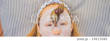 Young woman makes a face mask with snail mucus. Snail crawling on a face mask BANNER, LONG FORMAT 54615080