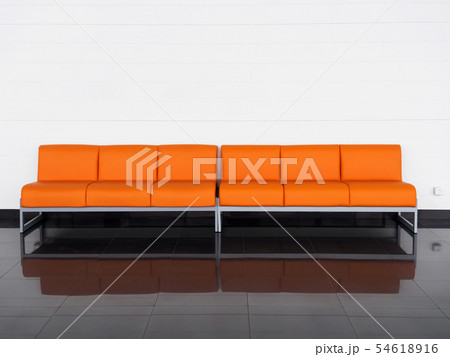 Empty orange sofa in the room near white wall. Waiting hall Empty orange sofa in the room near white wall. Waiting hall 54618916