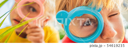 Boy and girl are looking in a magnifying glass against the background of the garden. Home schooling 54619235