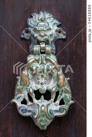 An old style decorative bronze door handle on a wooden door, the distinctive feature and symbol of 54638889