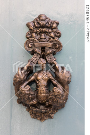 An old style decorative bronze door handle on a wooden door, the distinctive feature and symbol of 54638921