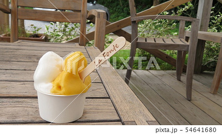 A gelato cup on a woody table at an open air deck 54641680