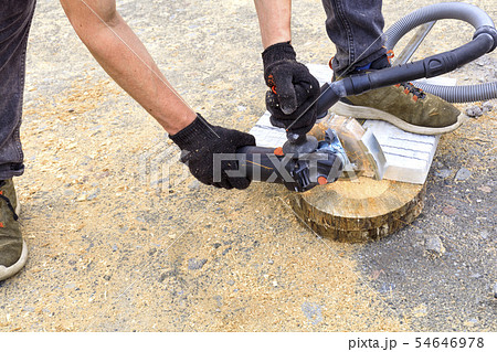 The worker cuts a metal plate and paving slabs The worker cuts a metal plate and paving slabs 54646978