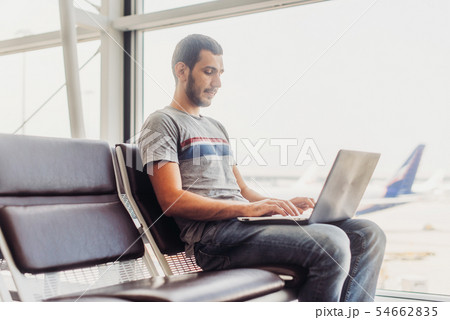 Young man using laptop in airport terminal 54662835