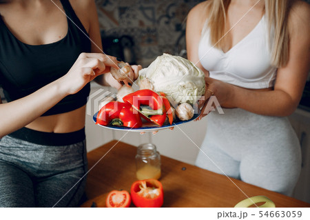 Two sports girl in a kitchen with vegetables Two sports girl in a kitchen with vegetables 54663059