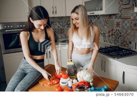 Two sports girl in a kitchen with vegetables 54663070