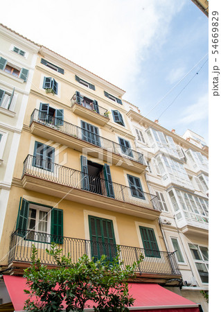 マヨルカ島の街並み　緑と青の遮光扉の付いた窓のある薄クリーム色の壁と石壁の家々 54669829