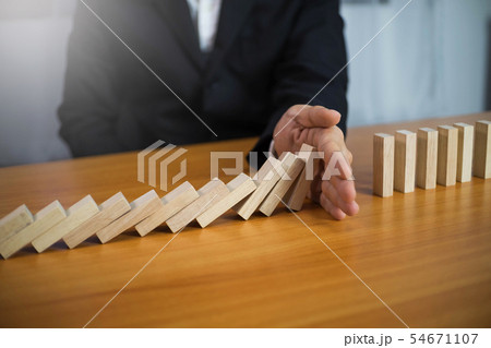 Businessman hand stops wood block continuous. 54671107
