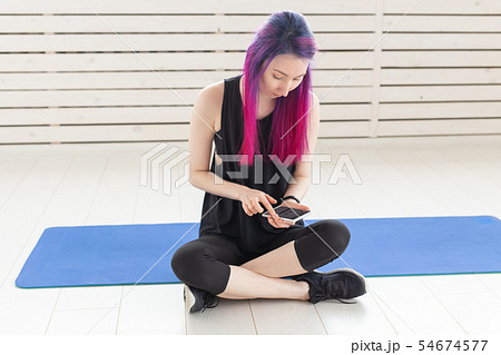 Pretty young mixed-race girl with purple hair is counting burned calories using an app on her 54674577