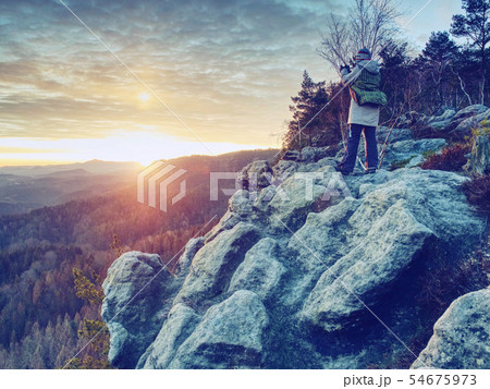 Hiker woman photographer takes photos from sharp Hiker woman photographer takes photos from sharp 54675973