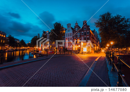 Amsterdam illuminated bridge with typical dutch houses in evening blue hour lights, Holland 54677080