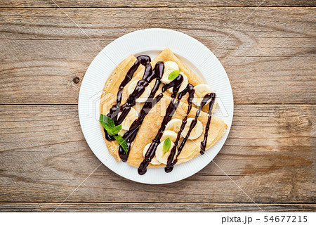 Crepes or blini with banana slices and chocolate sauce Crepes or blini with banana slices and chocolate sauce 54677215